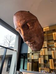 Masque monumental en cuivre ornant le bar