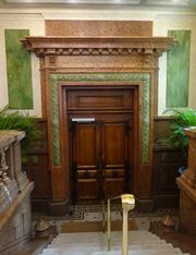 Effet de marbre rouge de l'encadrement de la porte avec patine verte des trois hauts-reliefs encastrés.