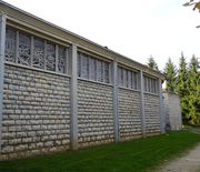 Façade latérale rythmée par l'alternance de piles de béton et de murs de pierre.