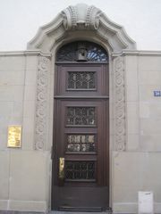Beau portail d'entrée néo-baroque avec agrafe et volutes sur la porte (ferronnerie) et de chaque côté de l'entrée.